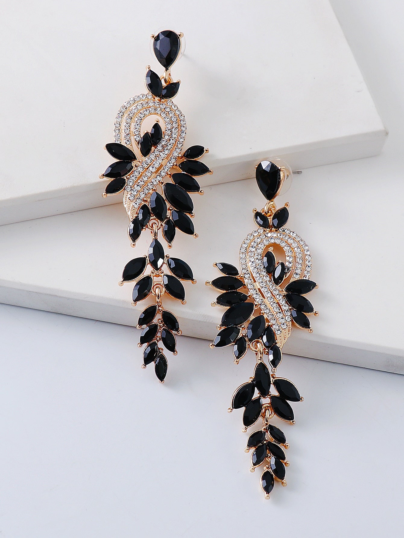 Ornate black and gold earrings on a white surface